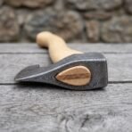 Damascus bearded axe head in close view showing the wooden wedge in the eye and the birch handle behind