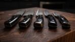 Close up of five black horn knife handles with pins and spacers lined up on an end grain wooden board