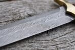 Damascus steel longsword blade lying on weathered wood, close view of the flowing pattern near the brass guard