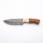 Damascus steel skinner knife with camel bone and wood handle laid flat on a plain white background