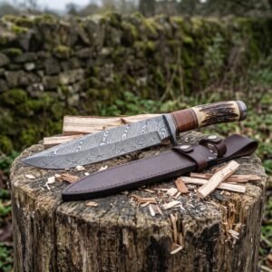 Damascus camp knife and brown leather sheath resting on a chopped tree stump among split kindling and wood chips