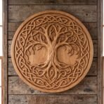 Round carved wooden Viking shield with tree of life and knotwork border hanging on a weathered plank wall