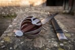 Basket hilt side sword with engraved steel shell guard, oxblood leather lining and compass pommel on a stone ledge