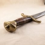 Close up of the lobed brass pommel, riveted wooden grip and brass quillons of a high carbon steel scimitar