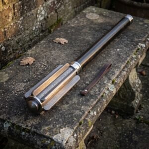 Damascus bar mace with a deeply fluted forge welded head and blackened steel haft resting on a weathered stone garden bench with fallen leaves