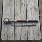 Damascus flail with a forge welded spiked ball head, brass collars, rosewood haft and hanging chain laid on a silvered timber table top