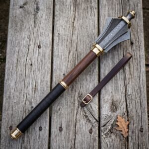 Damascus mace with six forge welded flanges, brass collars and a rosewood haft lying on a silvered timber table beside a buckled leather wrist strap
