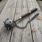Damascus steel flail with a spiked ball on a chain, patterned fore shaft and leather wrapped wooden haft on weathered planks