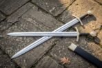 Full length view of an elven sword replica and black scabbard across flagstone paving, the engraved inscription running down the polished fuller
