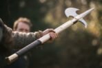 Halberd with steel spike and crescent blade on a pale ash haft with leather wrapped grip held out at arm length