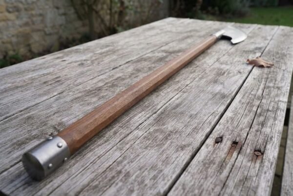 Hand forged high carbon steel bardiche with hardwood haft and steel butt cap, view along its length on a garden table
