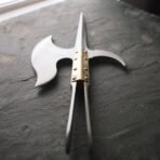 Hand forged polearm head with crescent axe blade, spike, hooked fluke and brass langet plates on dark slate