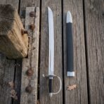 Polished steel cutlass and black leather scabbard with steel fittings laid side by side on weathered dock boards