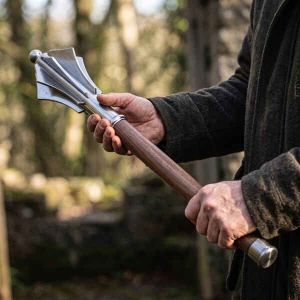Steel flanged mace with domed head and walnut haft held in two hands in a woodland clearing, polished steel ferrules