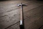 Steel halberd head with a crescent blade, back hook and top spike on a dark hardwood haft with steel langets on wooden boards