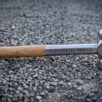 Hand forged 1095 steel blacksmith hammer with mirror polished ball pein head, Elder Futhark runes on the shank and an ash grip resting on grey gravel