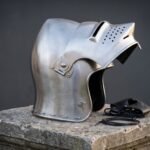Hand forged steel sallet helmet in polished 16 gauge mild steel with a raised hinged visor, long swept tail and a chased Vegvisir compass on a stone plinth