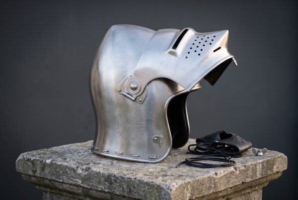 Hand forged steel sallet helmet in polished 16 gauge mild steel with a raised hinged visor, long swept tail and a chased Vegvisir compass on a stone plinth