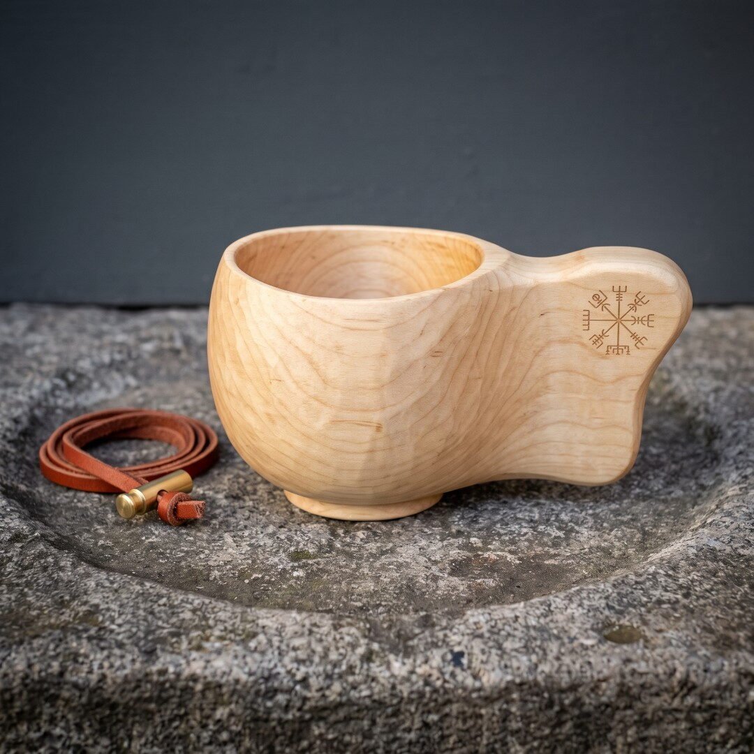 Gemini_Generated_Image_luz77bluz77bluz7 Hand carved wooden kuksa cup in pale birch with a Vegvisir burned into the solid handle standing on a weathered stone trough beside a brass tipped leather cord
