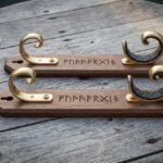 Pair of hand made walnut sword wall mount brackets with solid brass scroll hooks, felt lined cradles and Elder Futhark runes engraved into the wood on grey boards