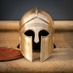 Hand raised brass Greek helmet of the Corinthian hoplite pattern with engraved meander brow band and crest ridge standing on warm sandstone steps