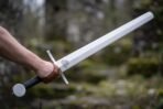 Arm holding a satin steel arming sword with etched valknut below a square bar guard, black grip and flat disc pommel