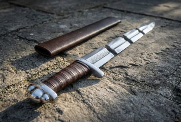 Arming sword with lobed steel pommel, brown leather grip and knotwork panel below the guard beside a brown scabbard