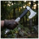 Bearded axe with Celtic knotwork etched along the edge, dark wood haft and wrapped grip held in a gloved hand