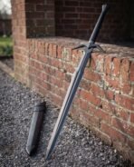 Black broadsword with diamond section blade and swept cross guard leaning on a brick wall beside its black scabbard