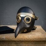 Black leather plague doctor mask seen head on, brass rimmed lenses, knotwork brass brow band and a stitched beak resting on stone