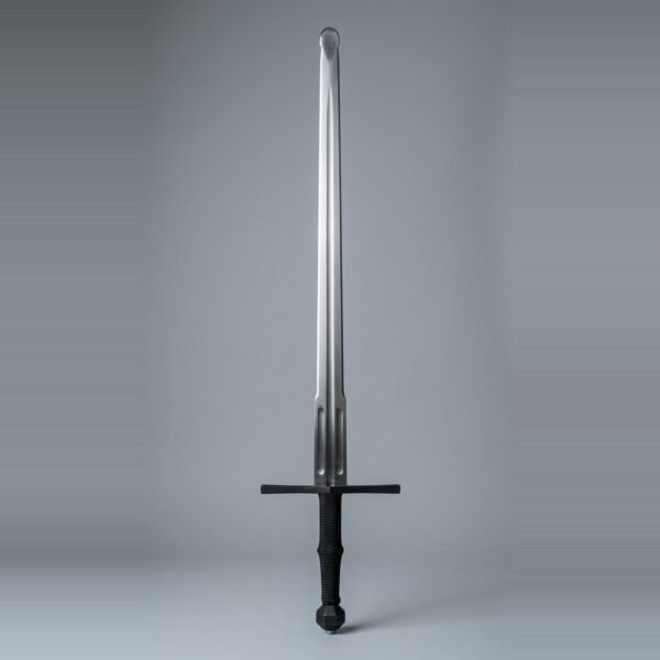Blackened longsword trainer with twin low fullers, faceted barrel pommel and black cord wrapped grip standing point up against a plain grey studio backdrop
