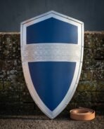 Blue and polished steel heater shield standing upright by an old brick wall with a coiled leather arm strap