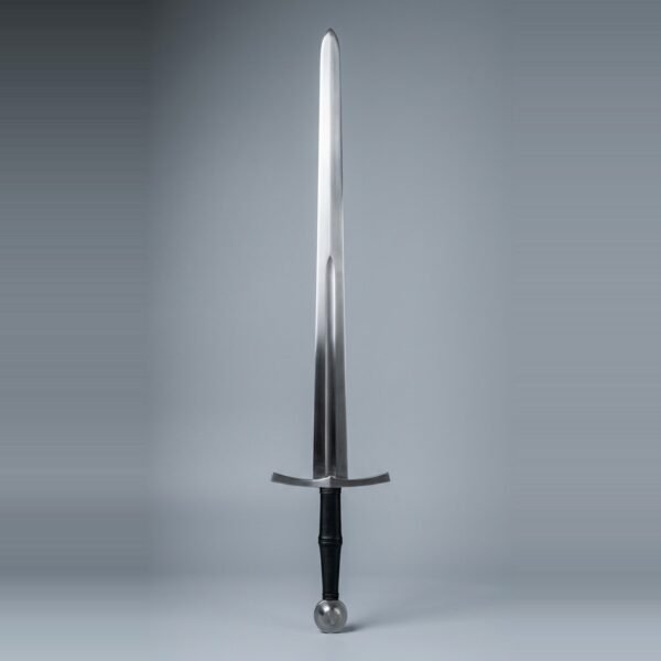 Blunt longsword for sparring with a fuller to mid blade, wheel pommel and black leather grip standing point up against a plain grey studio backdrop