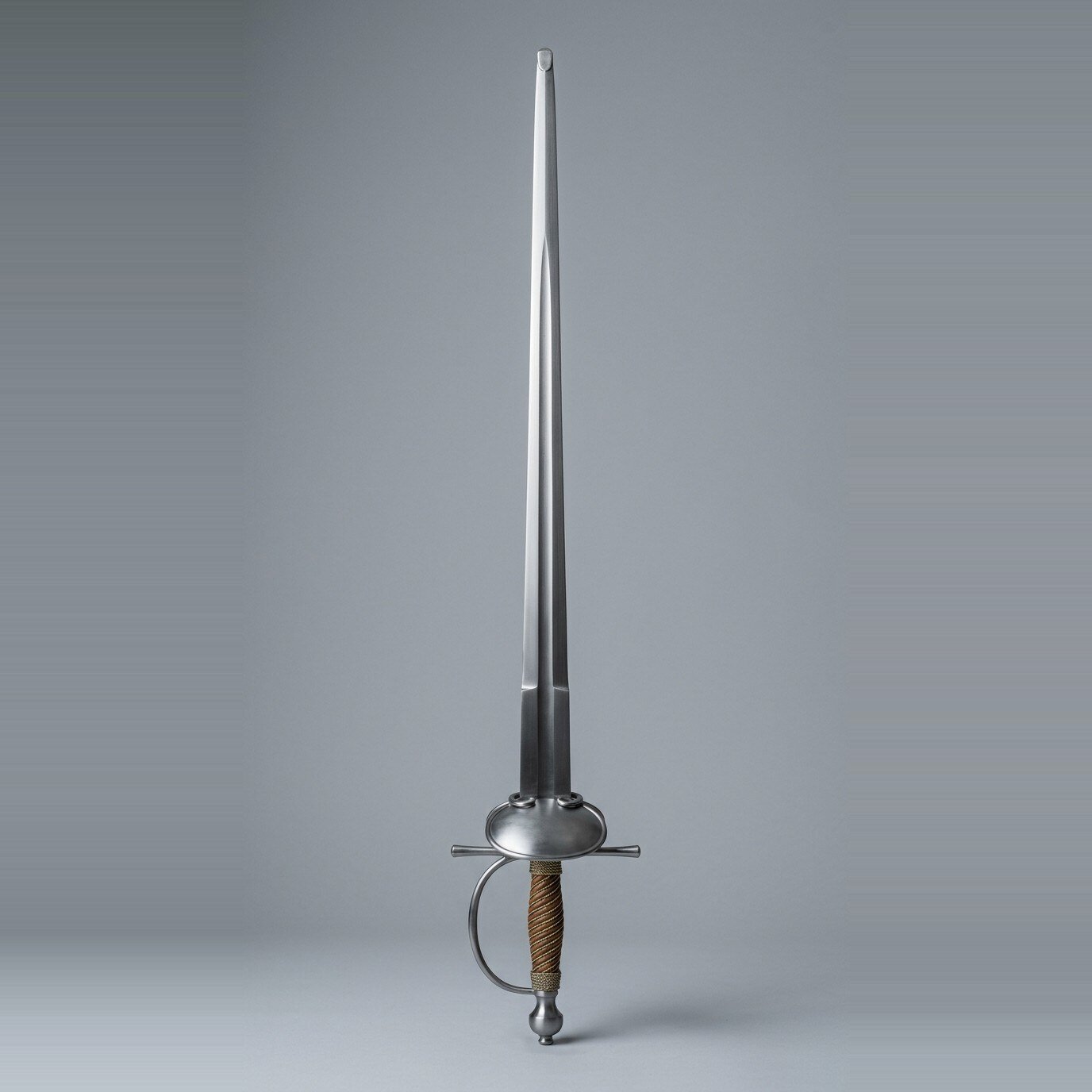 Lindmoor smallsword trainer with oval dish hilt Blunt smallsword trainer with a plain oval dish, arms of the hilt, stepped forte, brass wire wrapped grip and urn pommel standing point up against a plain grey studio backdrop