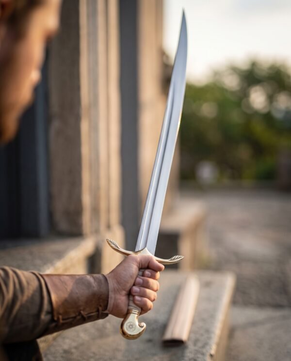 Brass hilted sabre with a slim curved blade and leaf shaped quillons raised in one hand beside a stone doorway