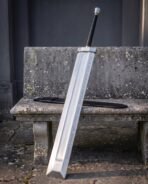 Broad slab greatsword with black grip and steel pommel leaning at an angle on a stone bench, rune etched flat facing out
