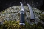 Close view of the cord wrapped tsuka and saya mouth on a viking katana laid across damp moss and pale lichen