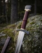 Close view of a Viking arming sword hilt with blackened knotwork pommel, oxblood leather grip and brass bands