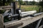 Close view of a Viking sword hilt with lobed blackened pommel and Valknut guard on a weathered gate rail beside its scabbard