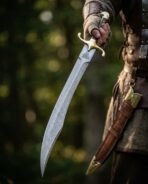 Curved Damascus long seax with brass guard, hooked brass pommel and Valknut etch held beside a tooled leather sheath