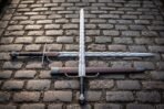 S curved steel crossguard sitting beneath the waves of a polished flame blade