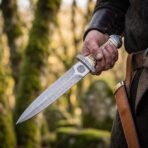 Damascus Celtic dagger with carved bone handle, spiral etched ricasso and tan leather sheath held at the hip