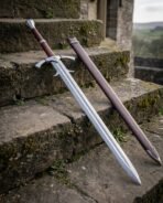 Damascus longsword with longship engraved guard and dark red grip leaning on old stone steps beside a brown scabbard