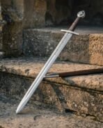 Damascus steel sword with a wheel pommel and dark wood grip leaning on sandstone steps with its timber scabbard laid alongside