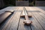Damascus sword with bronze toned five lobed pommel and coiled wire grip on a garden table beside a dark leather scabbard