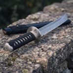 Damascus tanto with a shallow curved single edge and a valknut cut into the flat above the collar