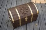 Domed wooden storage chest with studded brass bands and engraved lid next to a small brass padlock and key