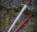 Etched longship panel on the downswept guard, fluted crown pommel above a burgundy grip