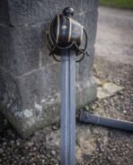 Etched triquetra panel on the outer plate of the blackened basket, a brass rosette rivet alongside