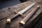 Faceted brass pommel closing the hilt of a pattern welded flame bladed short sword